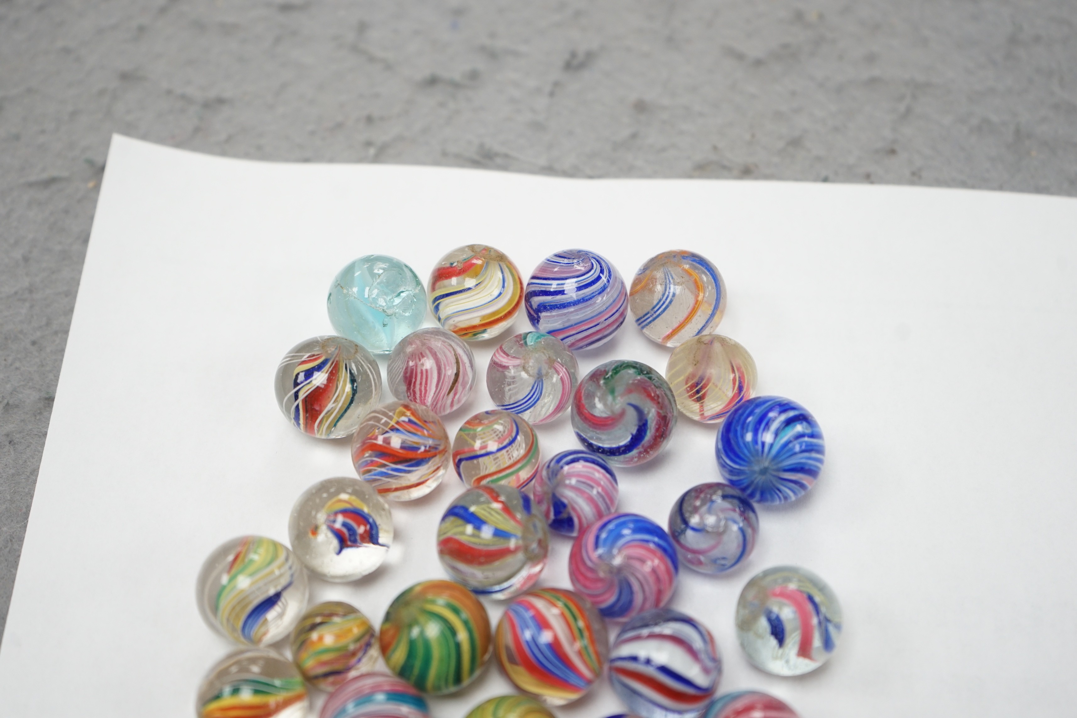 A mahogany solitaire board with a collection of latticino and marbled glass marbles